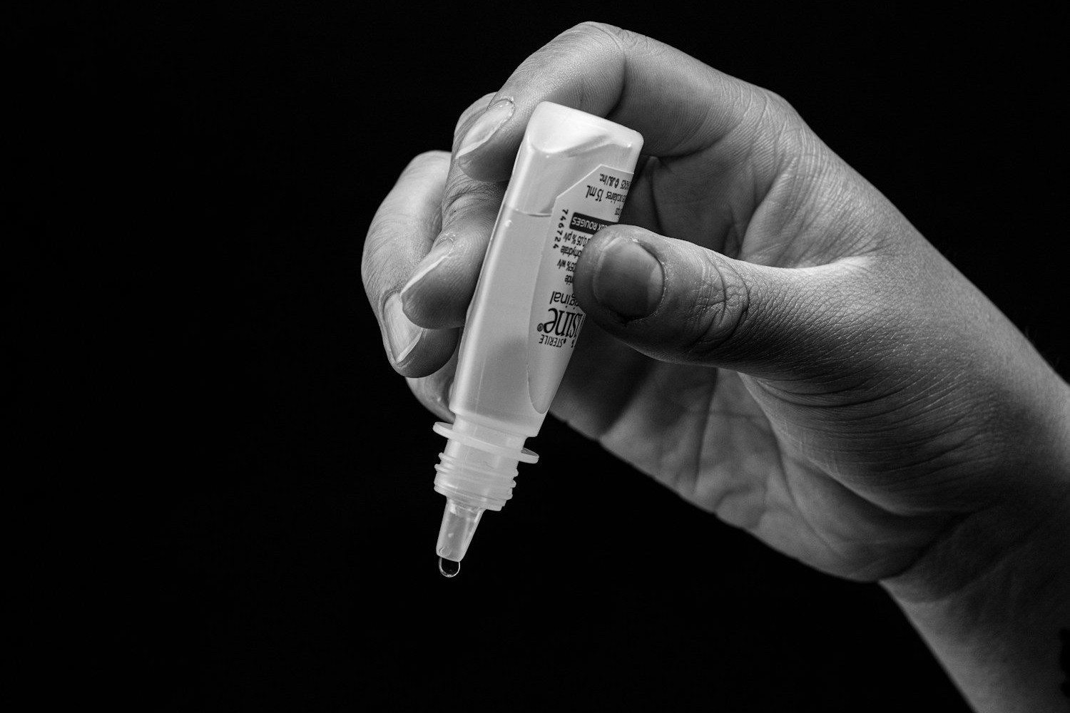 Hand holding eye drops, ready to administer.